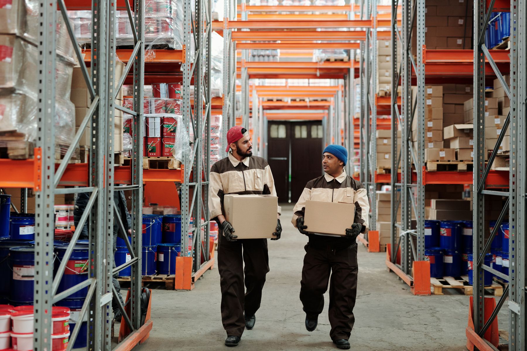 Warehouse team moving boxed inventory between storage aisles