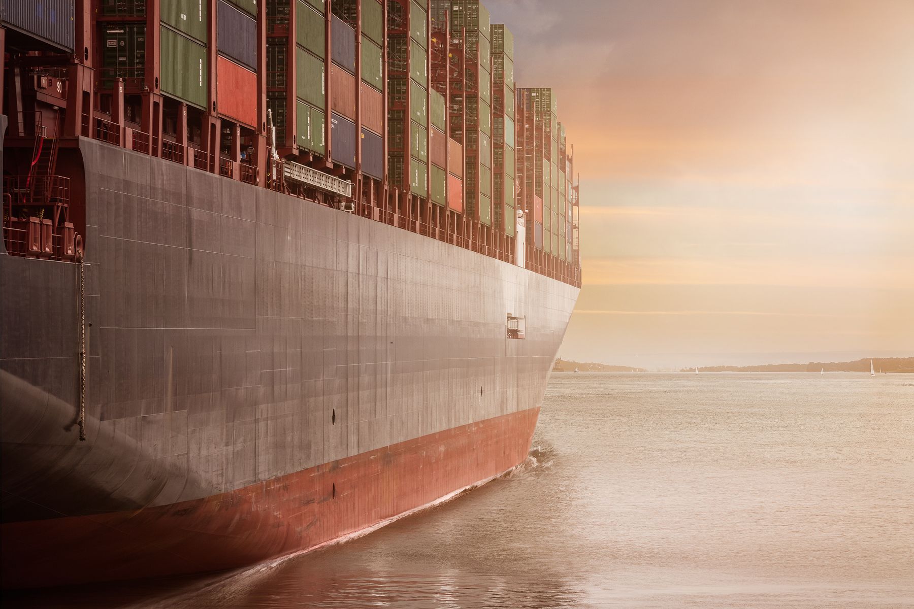 Container vessel alongside stacked cargo at a port terminal