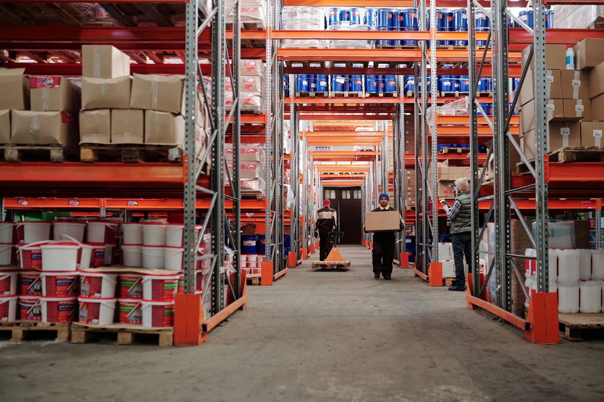 Warehouse workers handling boxed inventory between pallet racks